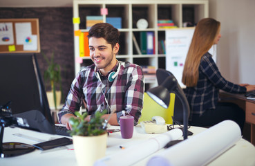 Two young people working on their computers, focus on the man