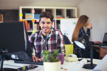 Two young people working on their computers, focus on the man 