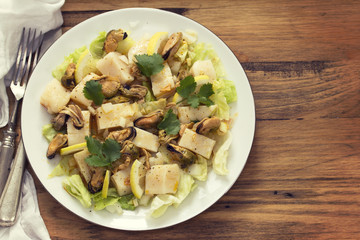 seafood salad on white plate on brown background