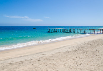 Long simple wooden jetty leading into turquoise blue ocean in Angola