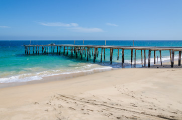 Long simple wooden jetty leading into turquoise blue ocean in Angola