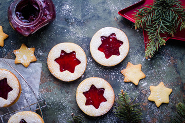Christmas Linzer cookies with raspberry jam on green table background. Top view and copy space
