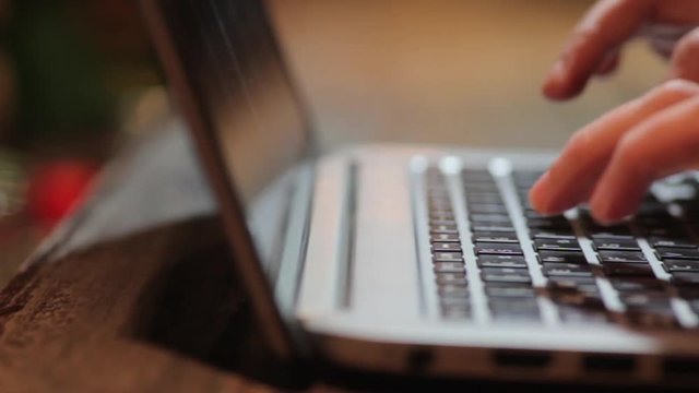 Panning shot of a woman's hands working on a laptop.