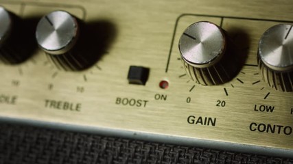 Close up of press boost button and turn up gain level on panel of guitar amplifier