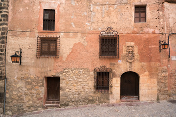 Fototapeta na wymiar Fachada de un edificio de un pueblo español antiguo con ventanas y puertas varias.