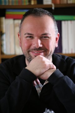 Portr&auml;t l&auml;chelnder Mann vor B&uuml;cherregal