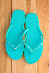 Ladies turquoise flip flops on the wooden floor closeup