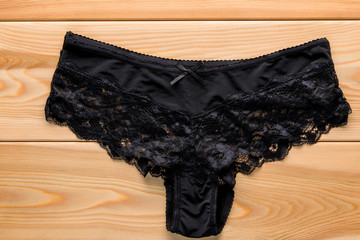 feminine satin panties with lace in black on the wooden floor cl
