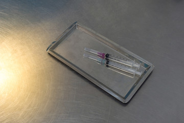 Syringe with needle on a steel tray