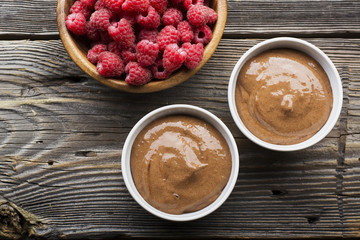 Chocolate Banana Smoothies served fresh juicy ripe raspberries with a sprig of mint in portioned bowls on  wooden background. The horizontal design