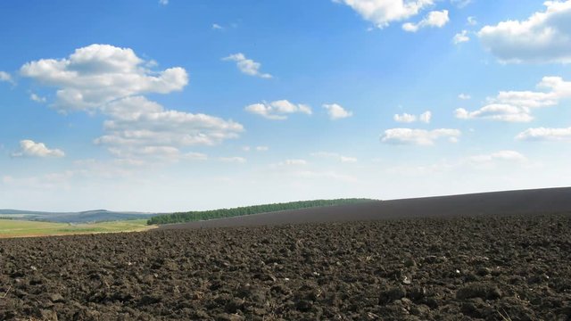 Plowed field and white clouds. Plough-land. Time lapse FHD