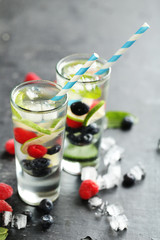 Detox water in glasses with berries on wooden table