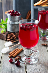 Fresh cranberry juice with cinnamon and anise in glass jars on the old wooden background. Selective focus.