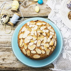 Simple homemade pecan pie decorated with petals of almond  a wooden background Serving Easter used blue and yellow colors, quail eggs, lavender flowers, vintage linen tablecloth handmade.