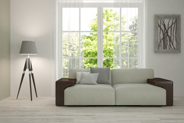 White room with sofa and green landscape in window. Scandinavian interior design