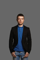 Portrait of stylish sudent in casual wear. European man look to the camera with serious face. Self-confident person on grey neutral background.