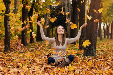 Autumn girl playing in city park. Fall woman portrait of happy lovely and beautiful young woman in forest in fall colors.