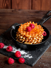 waffles with raspberries on wooden background