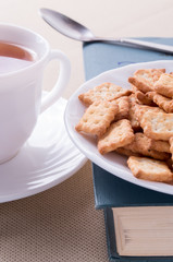 Cookies on old book next to a white cup of tea