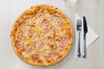 Pizza with ham and corn on the table