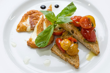 Delicious toast sandwiches with fried cheese, tomatoes, olive oil and basil