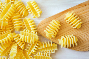 closeup of pasta with wooden spoon on white table.
