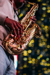 Saxophonist playing in the street with christmas lights