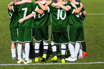 Sports team standing together on field. Football team motivated by coach. Youth soccer match