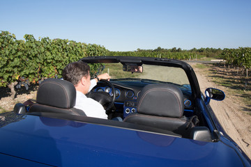 Rear view of a man driving his convertible car