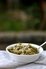 Bowl of creamy avocado pasta made with garlic, lemon juice and basil, served with grated parmesan cheese. Selective focus.
