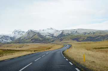 road through barren landscape with snow covered mountains in the background travel adventure in iceland panoramic scene