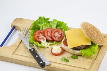hamburger with vegetables and fries on a wooden board, top view. / Tasty and appetizing hamburger cheeseburger.