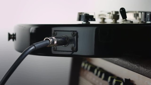 Plugging jack in electric guitar that lye on cabinet amplifier
