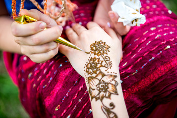Picture of human hand being decorated with henna tattoo, mehendi