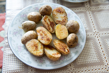 Traditional Russian baked potatoes with the peel with vegetable oil on a plate with a gray ornament