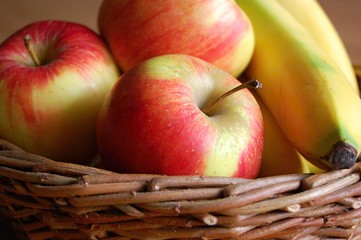 fresh red apples and yellow bananas in wicker basket