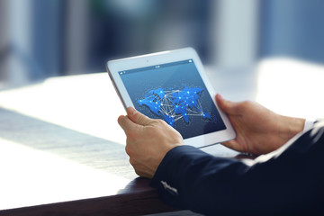 Male hands with tablet, closeup. World map with delivery network on screen. Logistics concept.