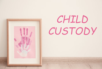 Painting with family palms prints near wall. Text CHILD CUSTODY on wall background