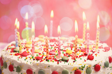 Lighted candles on birthday cake, closeup