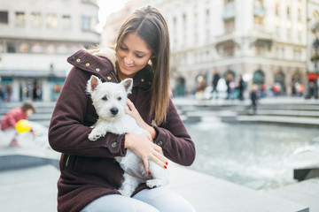 Beautiful young woman enjoying outdoors with her adorable west highland white terrier puppy.