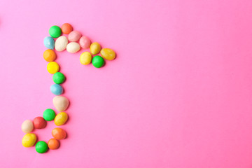 Musical note made of candies on color background