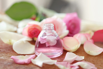 Essential oil with flower petals on wooden table