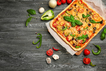 Delicious pizza with ingredients on wooden background