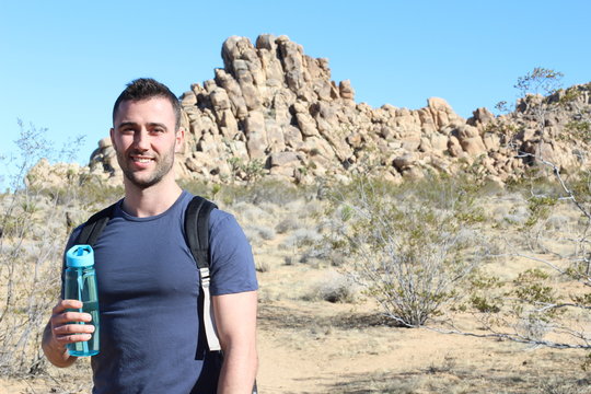 Grand Canyon travel - happy man mountain hiker with backpack on the rocky dry mountains