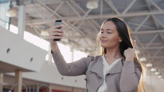 a beautiful girl taking selfie in airport terminal. Young business woman in mall with phone