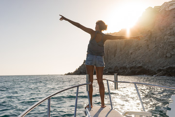 Young woman in the boat at sunset near the rock formations around the Arch in Cabo San Lucas, Mexico.