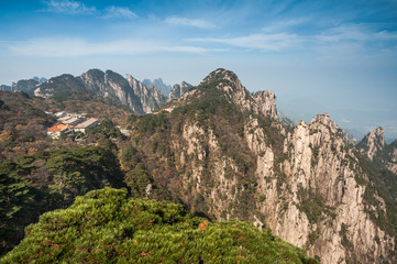 Fototapeta na wymiar Pine trees on cliff edge, Huangshan Mountain Range in China. Anhui Province - Scenic landscape with steep cliffs and trees during a sunny day.