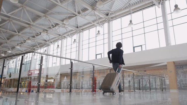Unrecognizable man with suitcase hurrying. Businessman runing with laggage in airport terminal or train station.