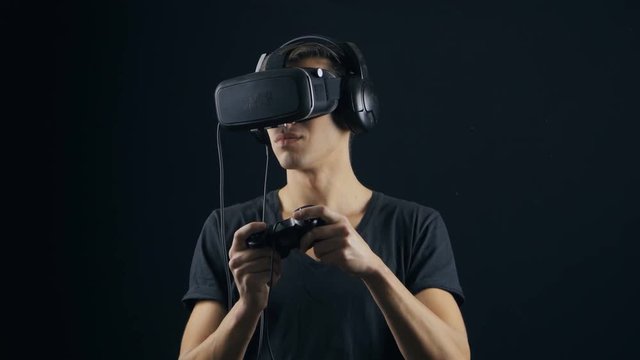 Virtual reality game. Man with pleasure uses head-mounted display in dark room