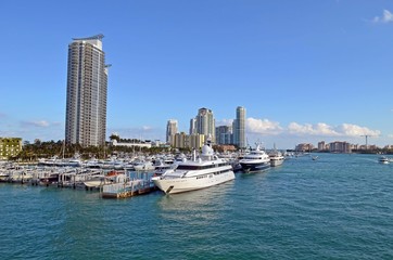 Fototapeta na wymiar Luxury boats and maya yachts moored at the Miami Beach Marina with luxury condominium towers in the background,